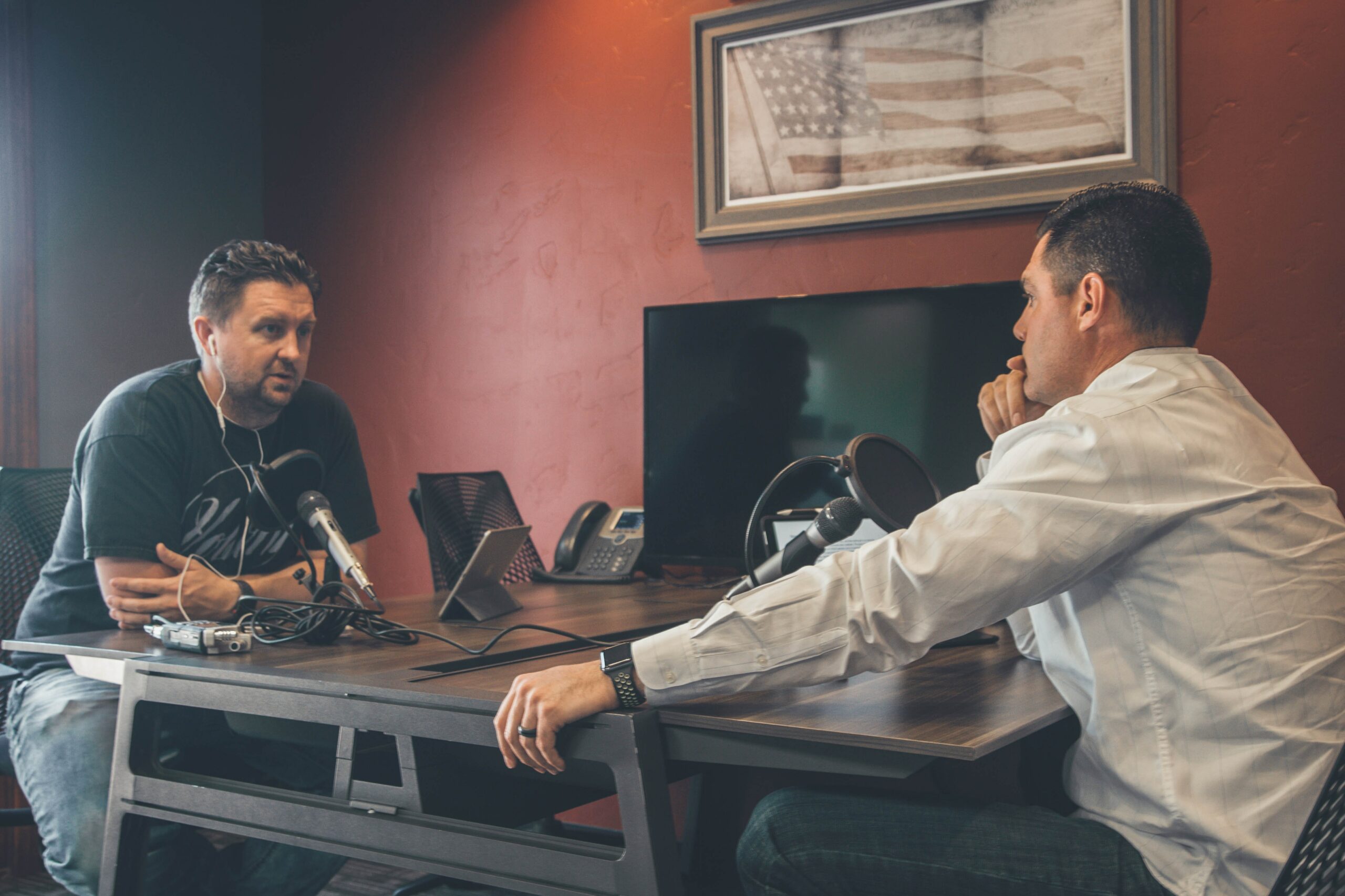two men sitting across a table recording an interview